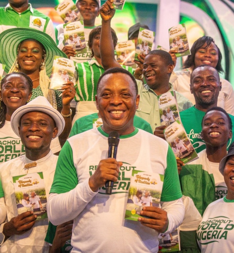 Zonal pastor centered among volunteers holding Rhapsody of Realities at a ReachOut Nigeria outreach